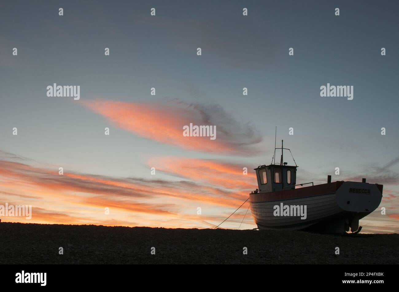La barca da pesca ha trasportato in su sulla spiaggia di ciottoli al tramonto, Dungeness, Kent, Inghilterra, Regno Unito Foto Stock