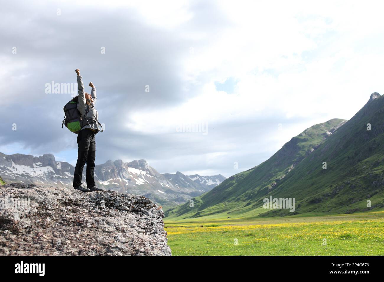 Escursionista entusiasta che celebra l'innalzamento delle armi in montagna Foto Stock