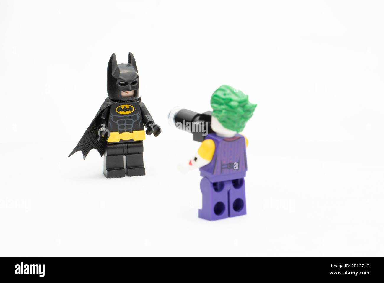 Un Joker Lego con una macchina fotografica rivolta verso Batman, statuine della DC Comics, isolate su sfondo bianco Foto Stock