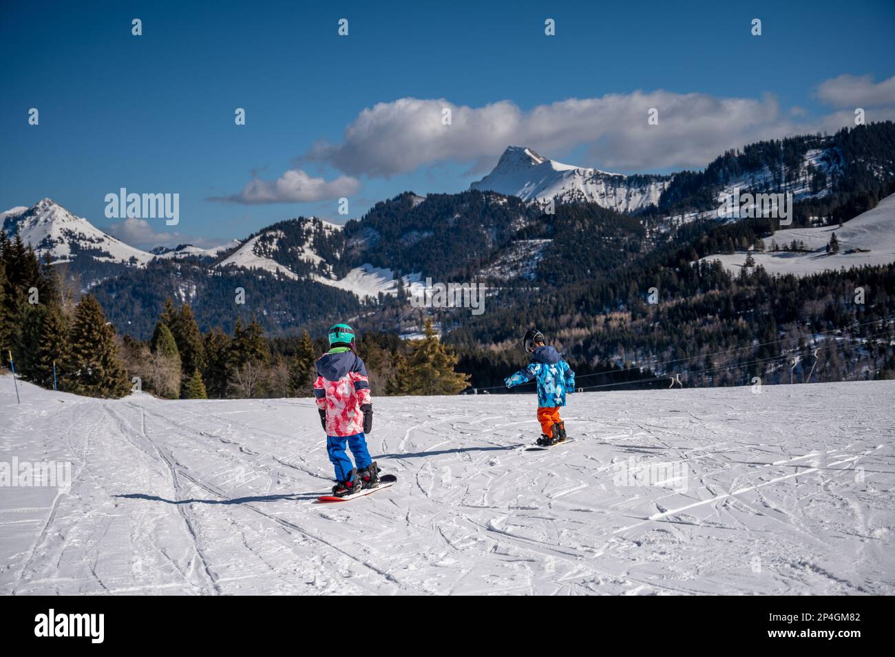Sci per bambini sulla neve. Un ragazzo asiatico e una ragazza snowboard. Sport invernali. Les Pleiades, Svizzera. Foto Stock