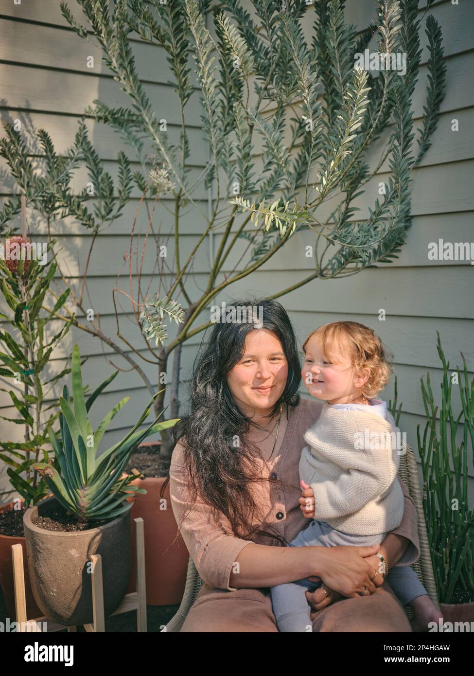 Madre e figlia circondata da piante sul portico anteriore Foto Stock