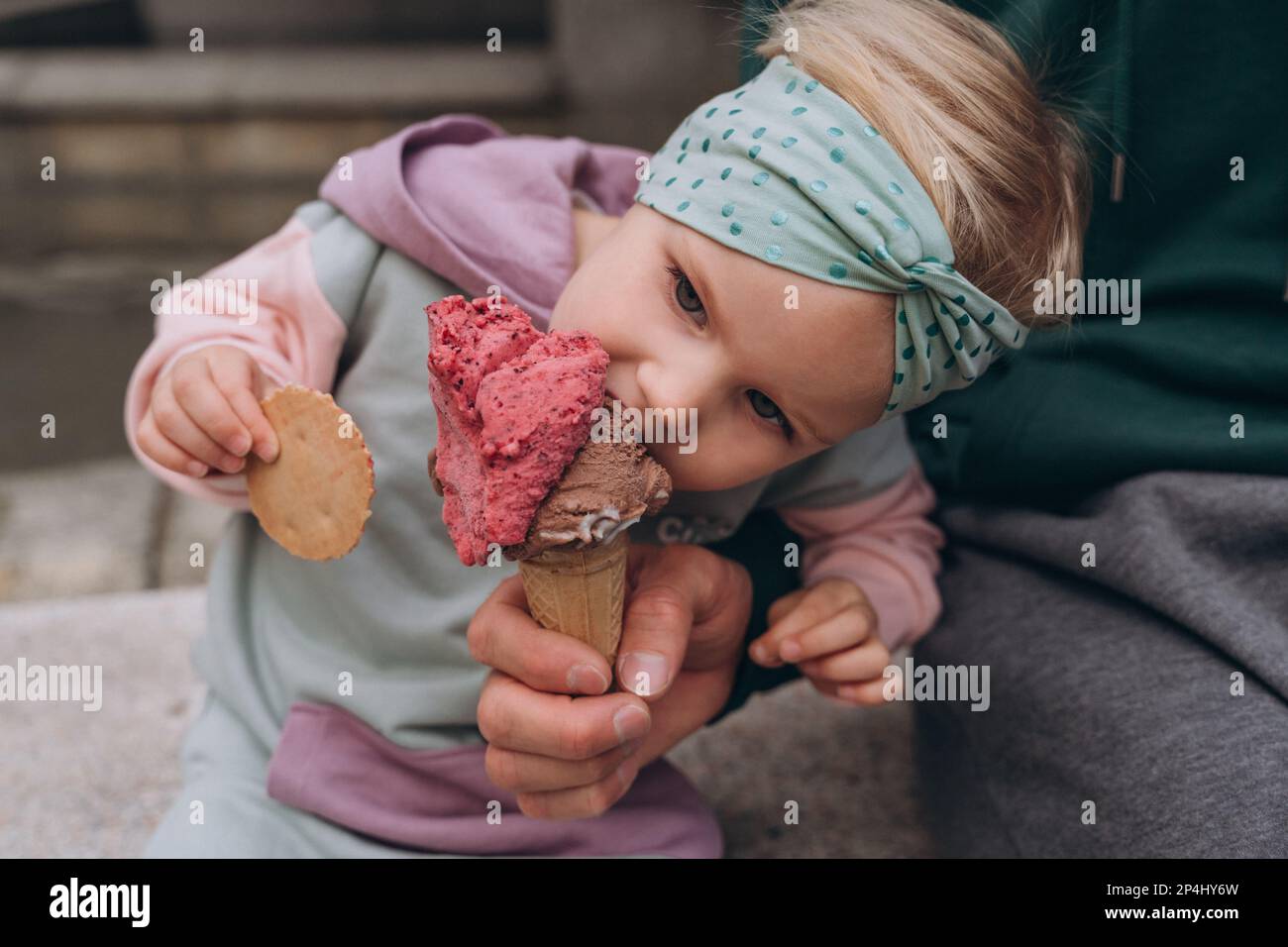 Papà alimenta la figlia con gelato alla bacche in un cono di waffle, primo piano Foto Stock