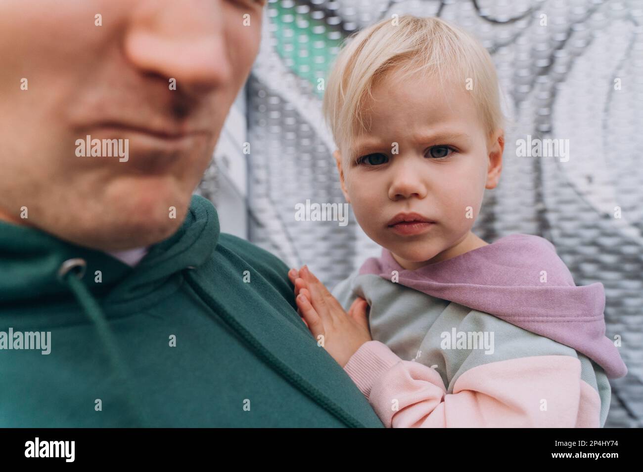 Papà che tiene in braccio una figlia di due anni con un'espressione seria Foto Stock