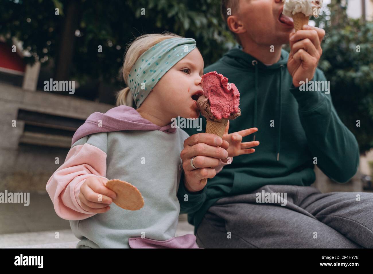 Uomo e bambino che mangiano gelato italiano per strada Foto Stock