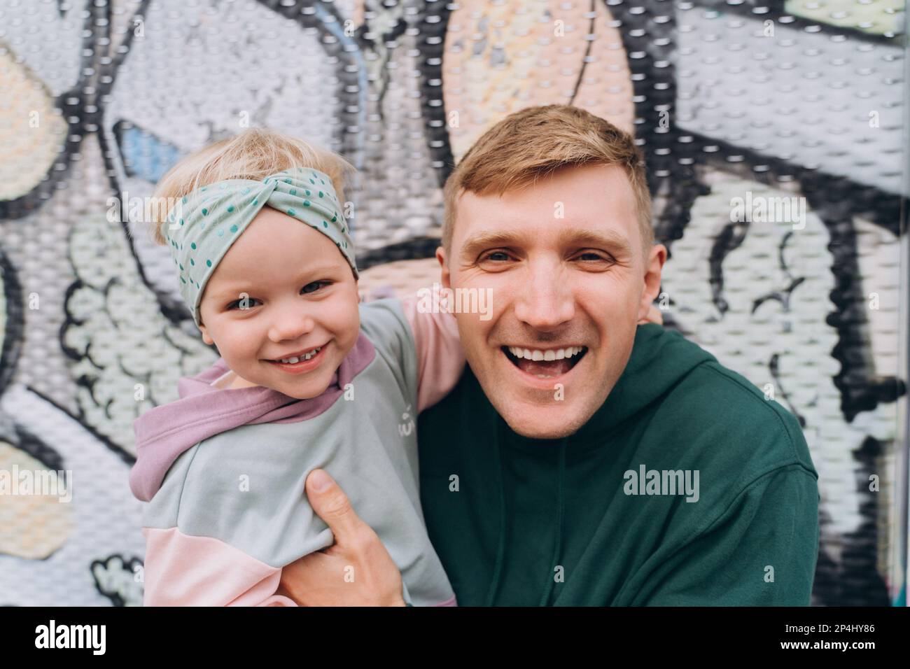 Primo piano ritratto di felice papà e figlia in felpe cappuccio, colori pastello Foto Stock