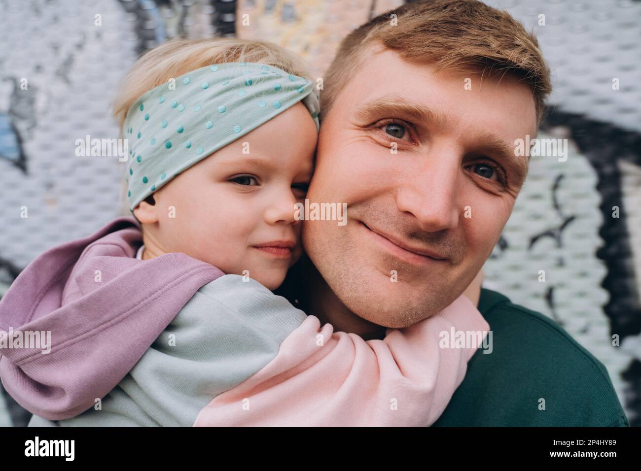 Primo piano ritratto di padre e figlia in felpe con cappuccio, colori pastello Foto Stock