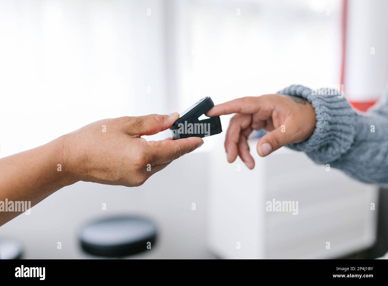 Mano del medico che tiene il pulsossimetro sul dito del paziente adulto Foto Stock