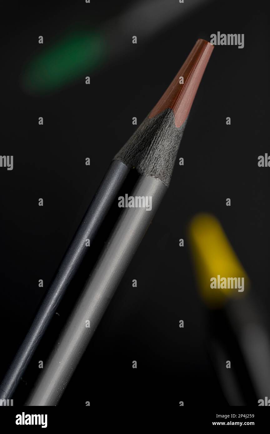 Le matite colorate con base nera si divaricano in uno spazio nero. Foto Stock