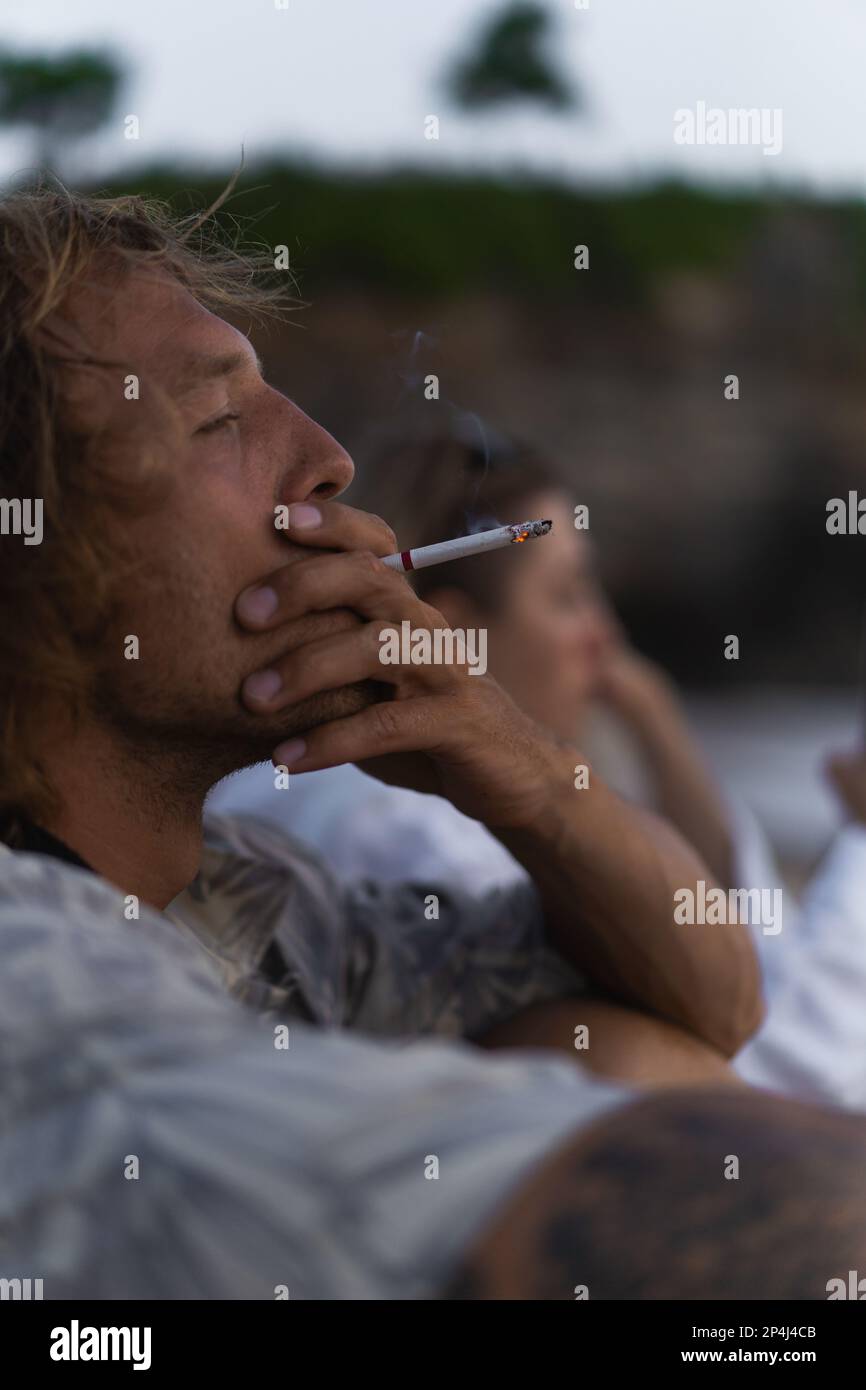 Uomo che fuma una sigaretta vicino all'oceano Foto Stock