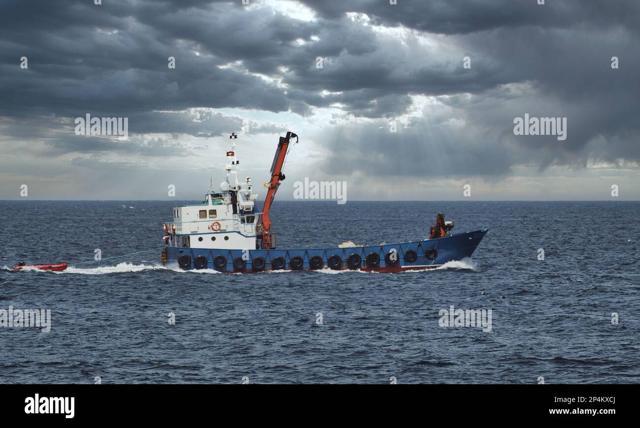 Una barca da pesca con palangari in mare aperto contro un cielo spettacolare sopra l'orizzonte Foto Stock