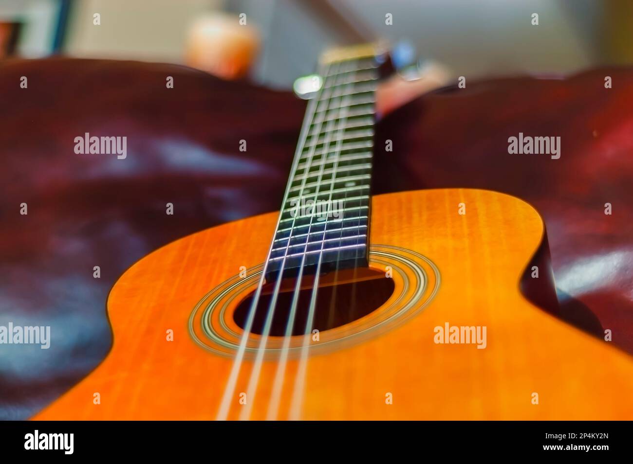 Un primo piano di chitarra acustica classica con corde di nylon, sdraiata su un divano. Foto Stock