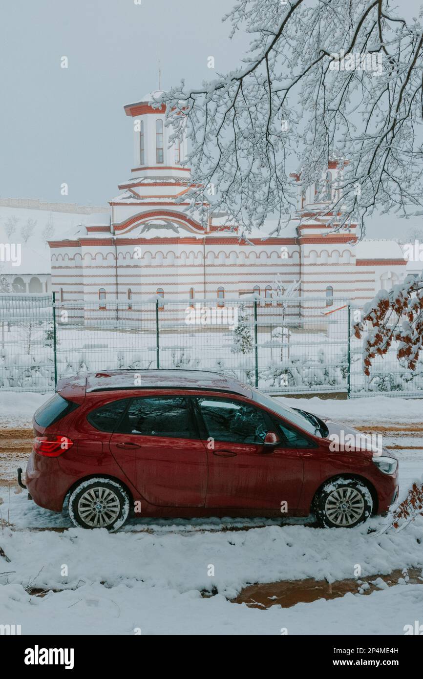 Auto rossa in inverno vicino a una chiesa Foto Stock