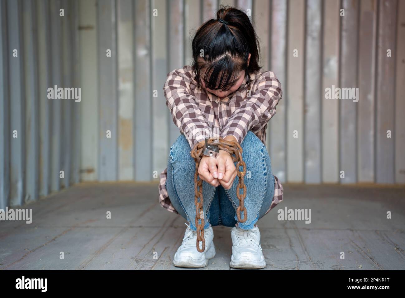 Donna intrappolata nel contenitore di carico attendere il traffico di esseri umani o lavoratori di fronte, donna che tiene la chiave padronale in attesa di aiuto holp, donna incatenata al suo wrinis Foto Stock