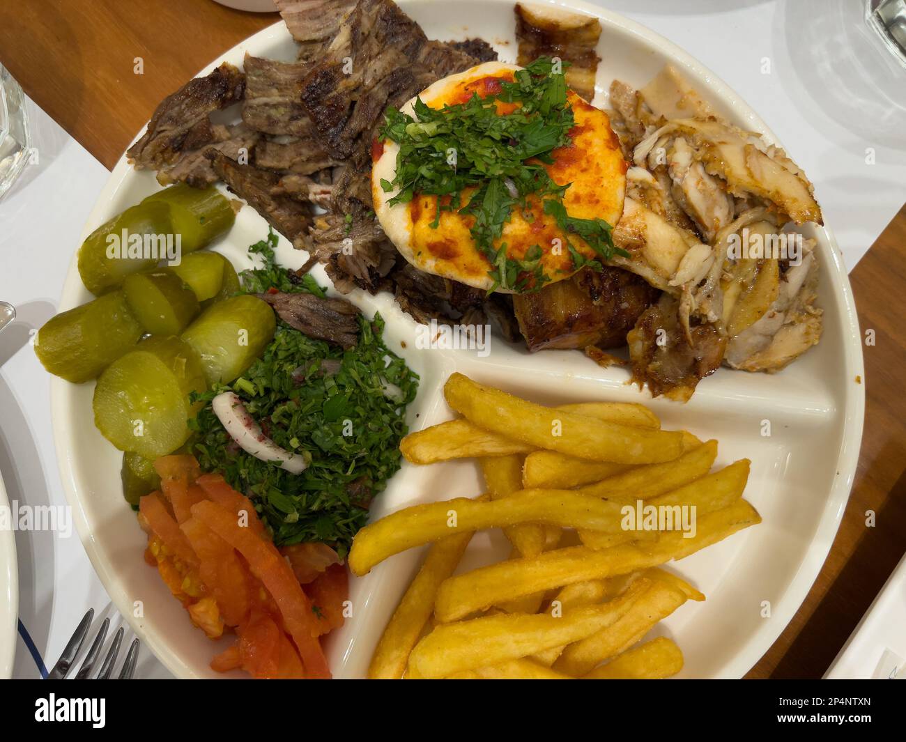 vista dall'alto verso il basso di un piatto di shawarma pronto a mangiare, servito in un piatto bianco e posto su un tavolo di legno. Cucina araba o mediorientale. Foto Stock