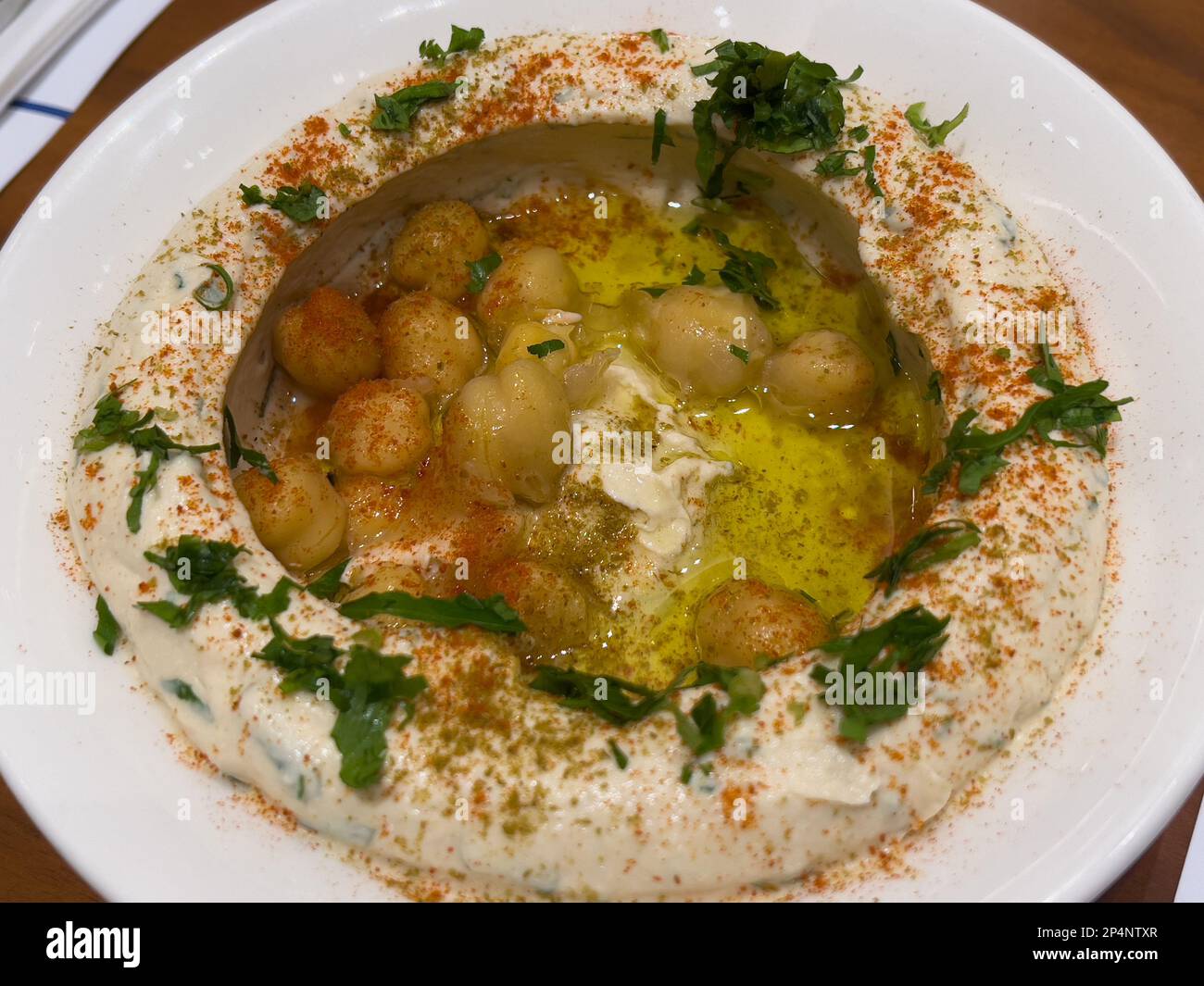 primo piano di una ciotola di hummus posta su un tavolo. Cucina araba o mediorientale. Foto Stock