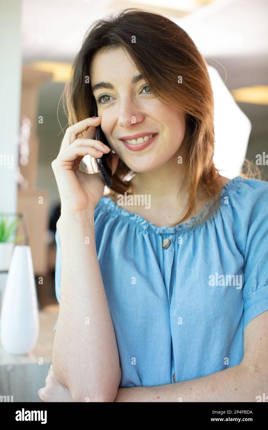 donna sorridente che parla al telefono a casa Foto Stock