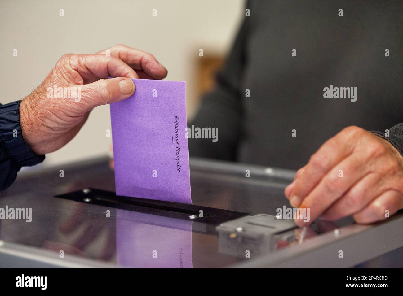 Un anziano che inserisce il suo voto attraverso lo slot del voto durante le elezioni. Foto Stock