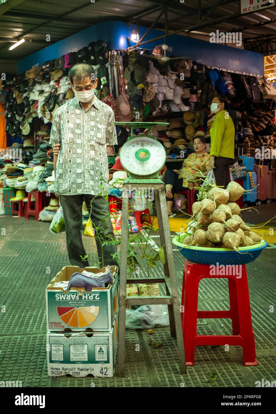 Un uomo si ferma a guardare alcune piante e verdure da una serie di scale nel mercato centrale, Phnon Penh, Cambogia. Foto Stock