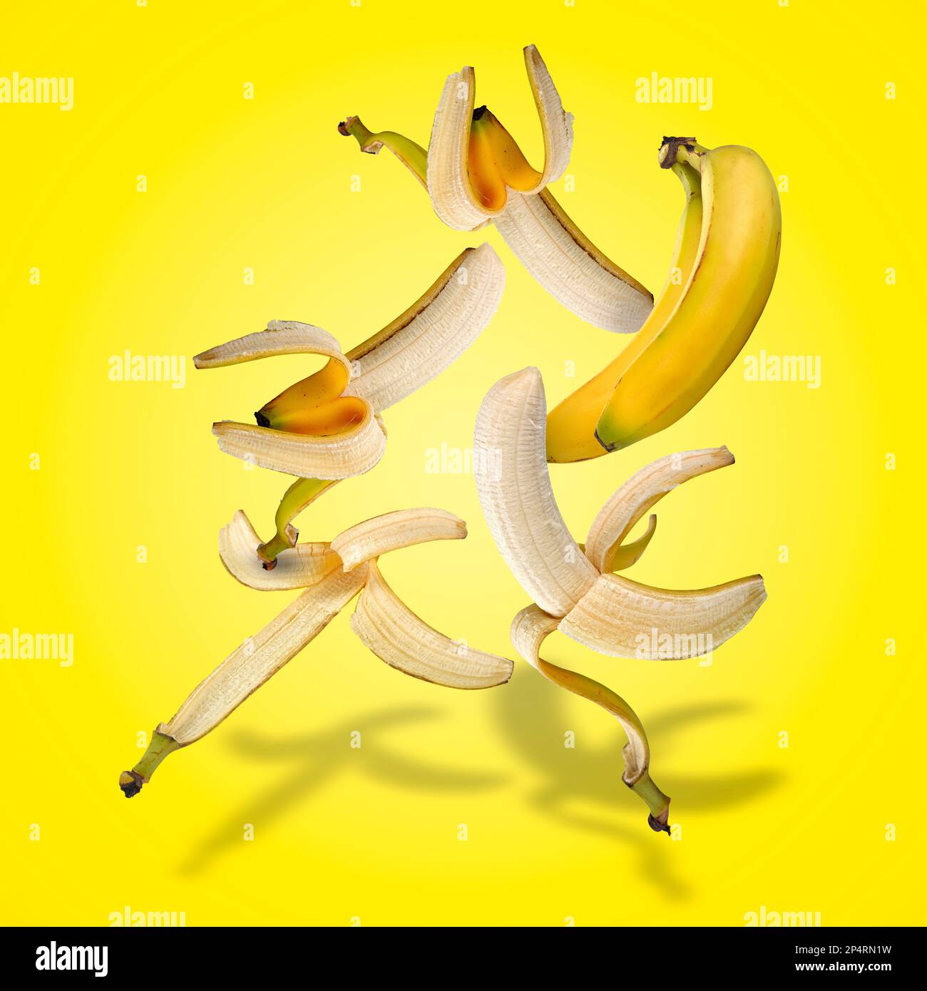 Set galleggiante di banane con ombre su gradiente giallo Foto Stock