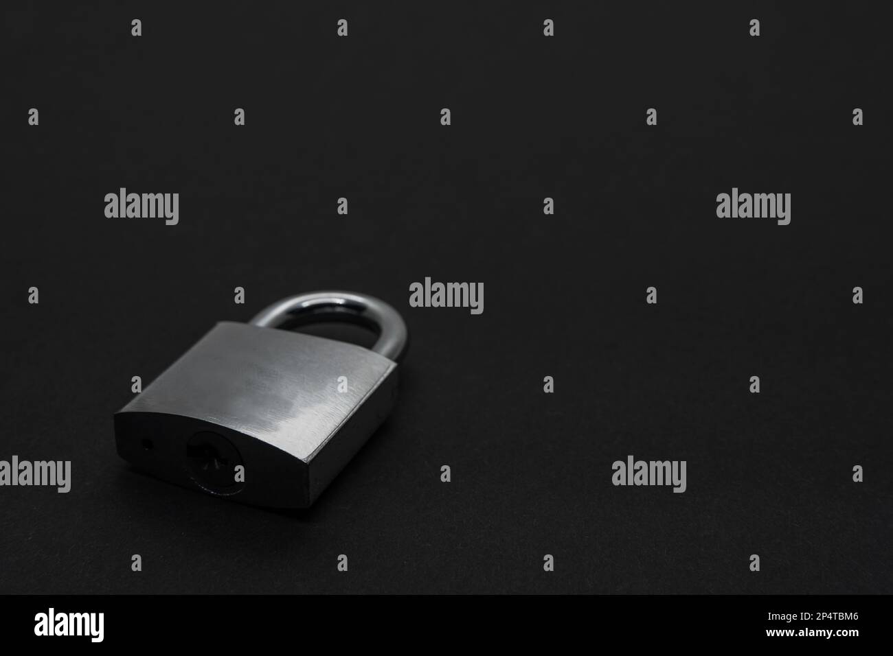 Lucchetto in acciaio su superficie nera con spazio di copia Foto Stock