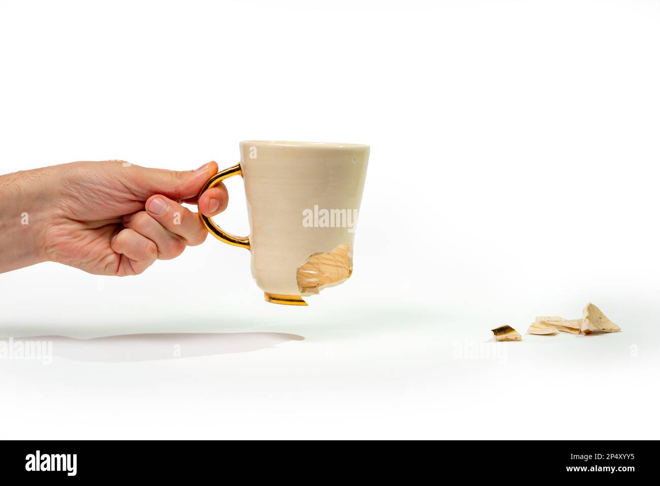 Uomo che tiene rotto tè tazza isolato su sfondo bianco. Primo piano del braccio che tiene la tazza di caffè incrinata Foto Stock