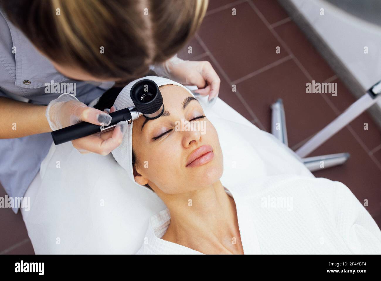 Il dermatologo medico esamina la pelle del viso del cliente del salone di bellezza con una lente dermatologica. Dermatoscopia. Spazio libero per il testo. Foto Stock