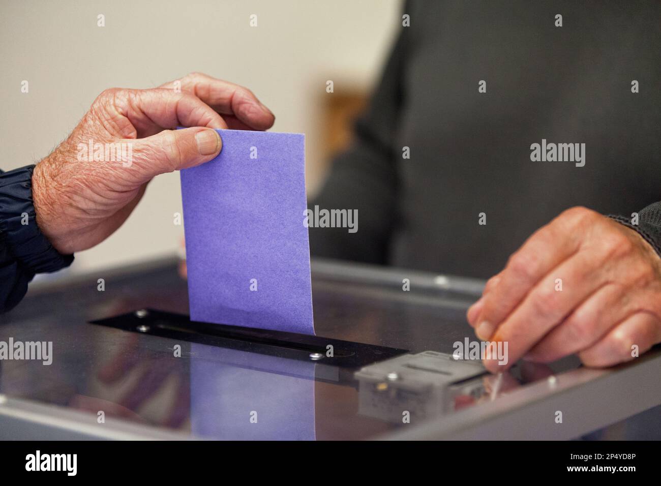 Un anziano che inserisce il suo voto attraverso lo slot del voto durante le elezioni. Foto Stock
