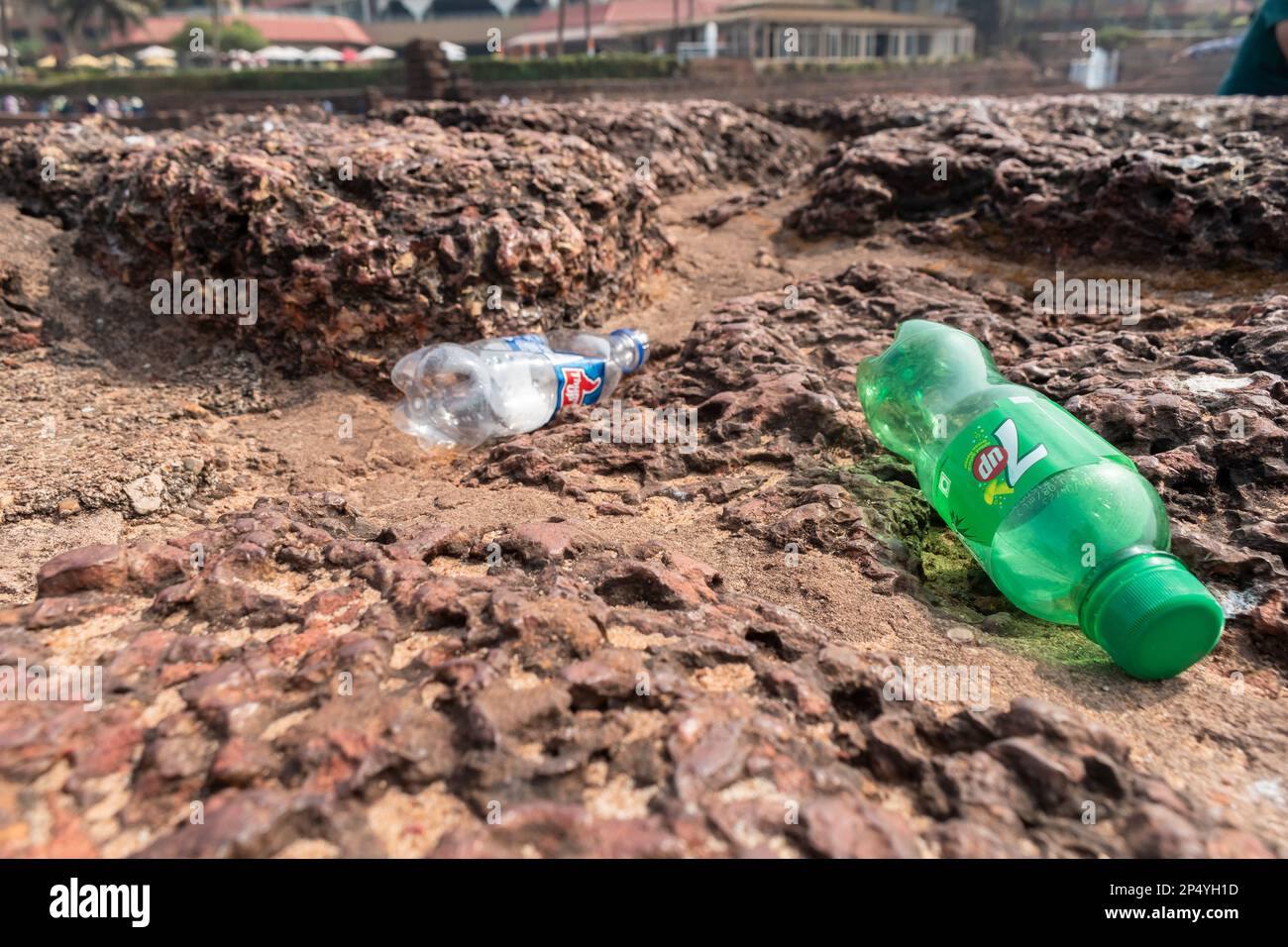 Candolim, Goa, India - Gennaio 2023: Bottiglie di plastica e rifiuti disseminati sul muro di mattoni lateriti di un antico forte portoghese di epoca a Sinquerim. Foto Stock