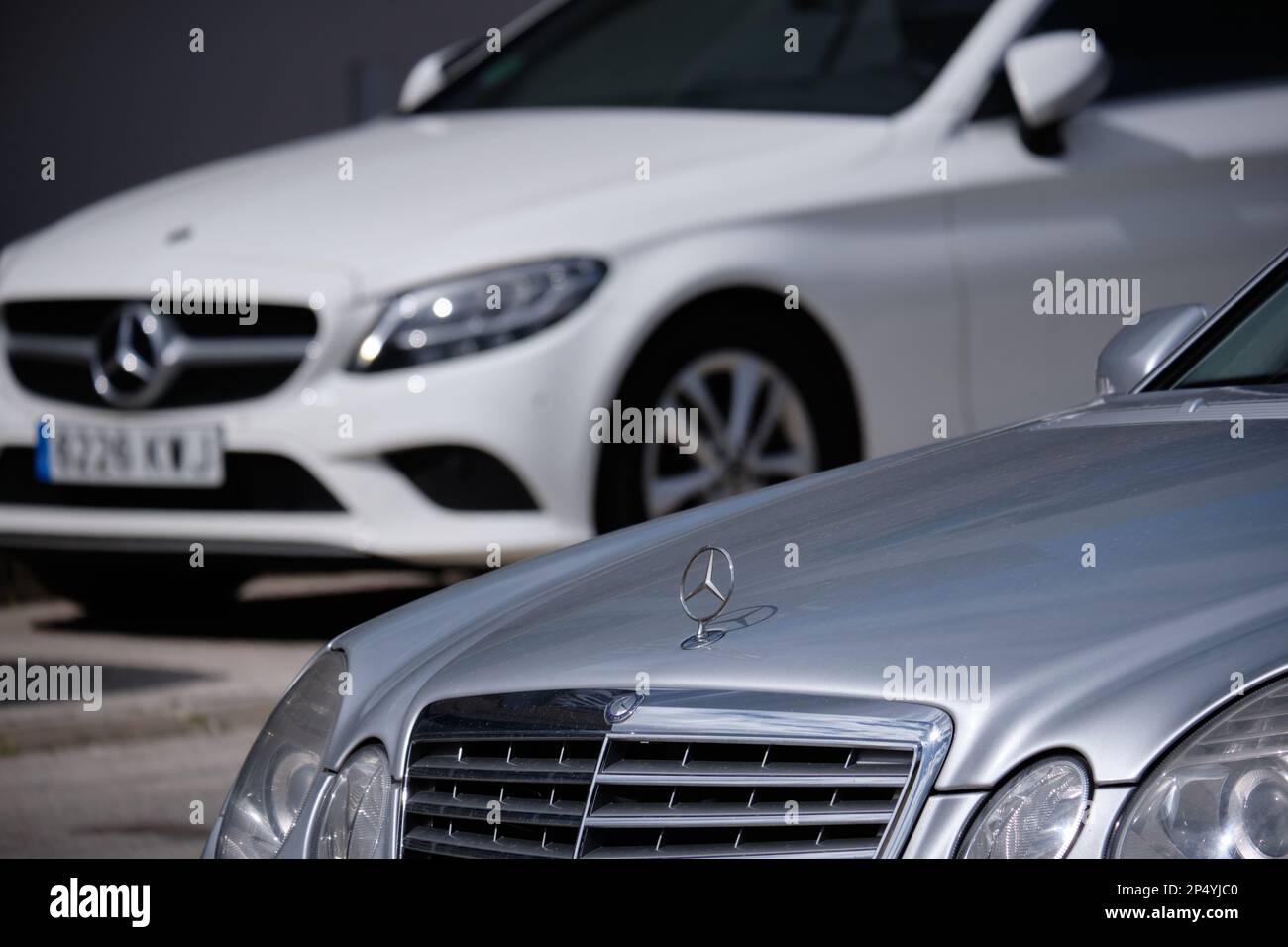 Primo piano di un emblema Mercedes-Benz con un'altra Mercedes alle spalle. Foto Stock