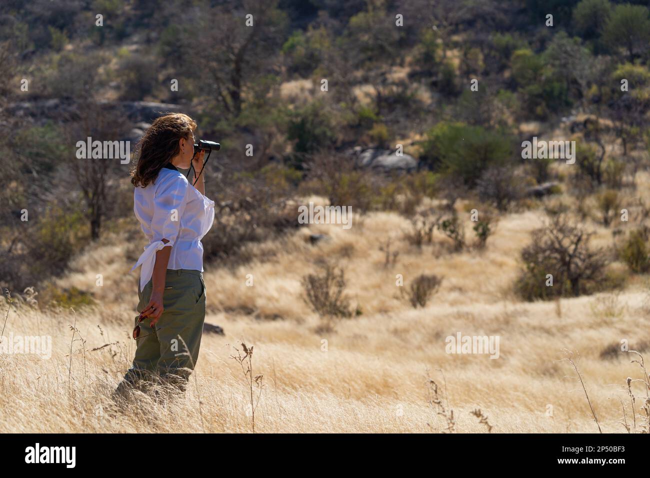 Giovane turista femminile che si erge fuori e guarda la fauna selvatica di samburu con binocoli in kenya Foto Stock