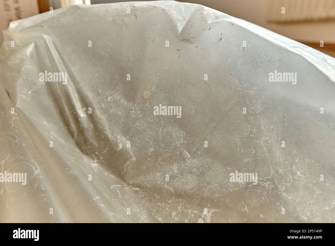 Rivestimento di pavimenti in legno con foglio trasparente per la verniciatura di pareti. Macchie di vernice bianca, macchie e polvere sulla pellicola di plastica trasparente. Foto Stock