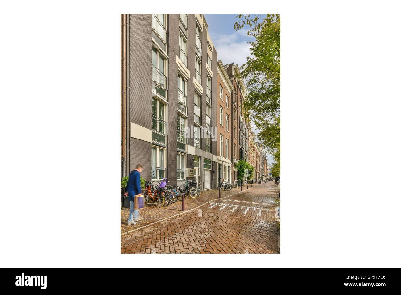 persone che camminano lungo la strada di fronte ad un edificio di appartamenti con biciclette parcheggiate su entrambi i lati degli altri edifici Foto Stock