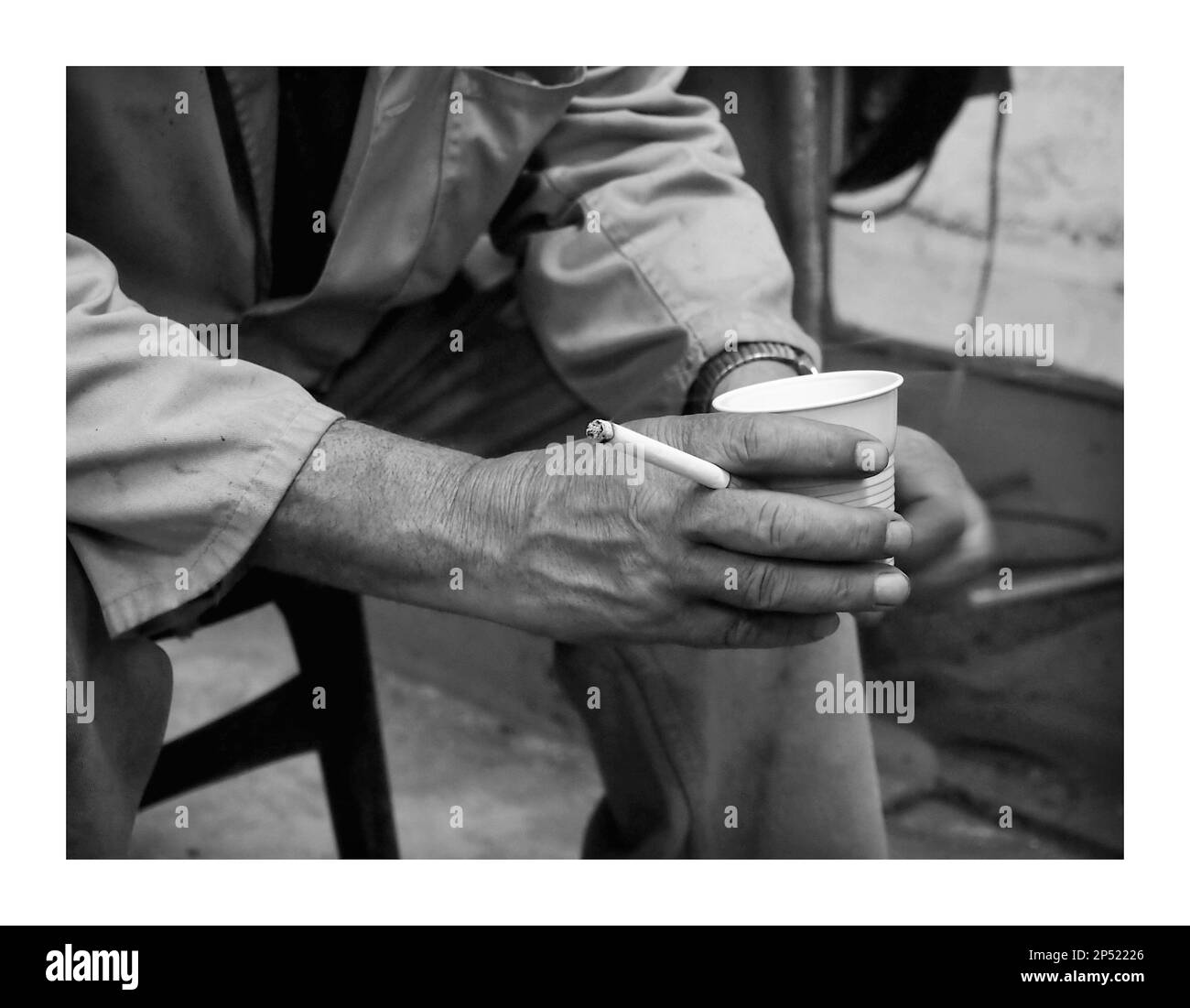 Una persona in possesso di una bevanda e sigarette Foto Stock