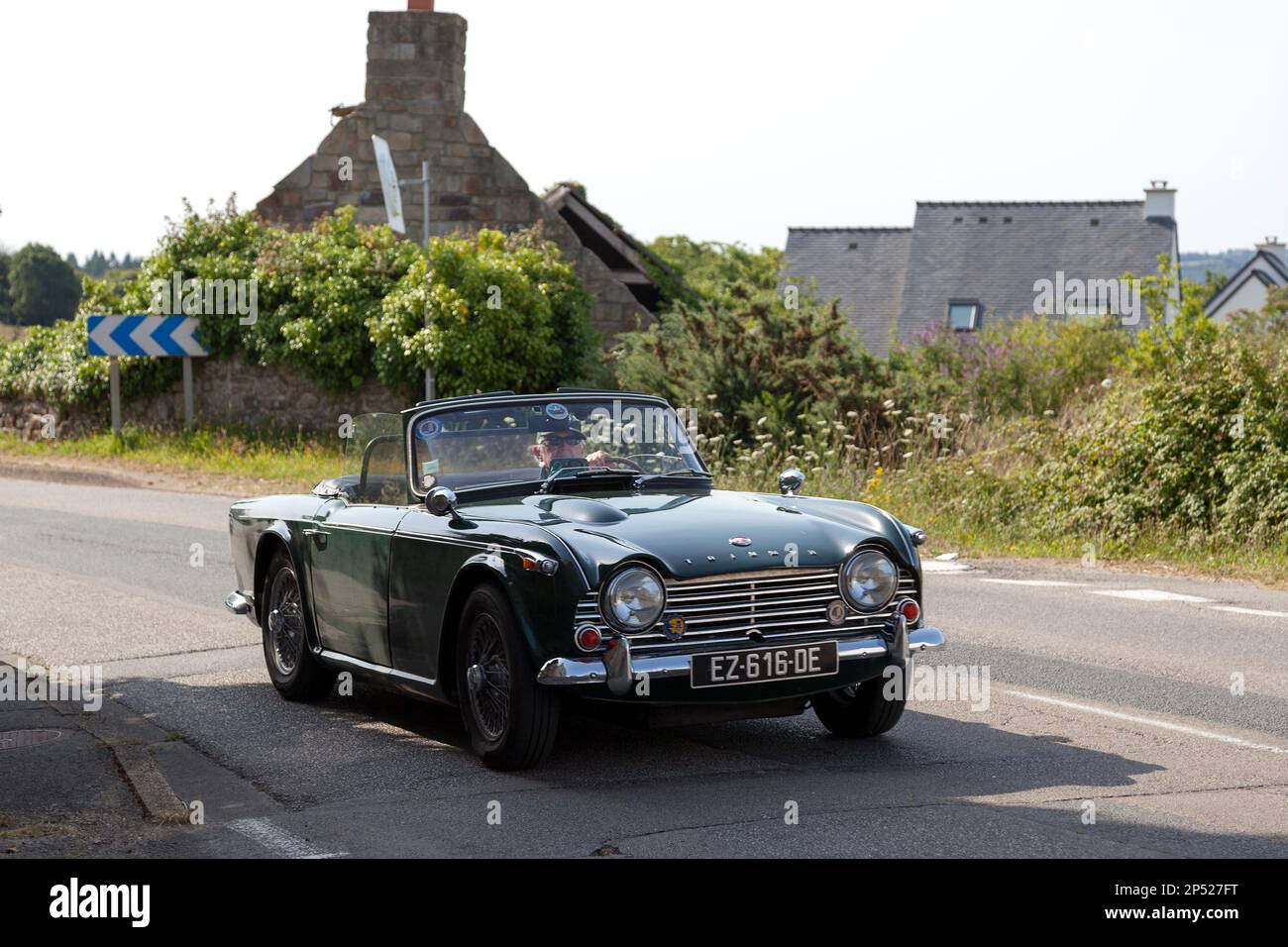 Kerlaz, Francia - Luglio 17 2022: Coppia in pensione in crociera in un verde Triumph TR5 sport convertibile. Foto Stock