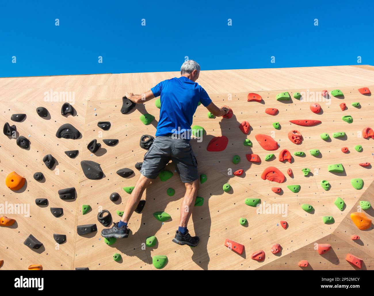 uomo di sessantacinque anni sulla parete di arrampicata all'aperto. Foto Stock