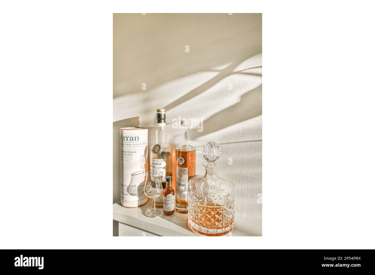 Amsterdam, Paesi Bassi - 10 aprile, 2021: Alcune bottiglie e bicchieri seduti su uno scaffale con il sole che splende attraverso il muro dietro di loro, come se fosse il momento di farlo Foto Stock