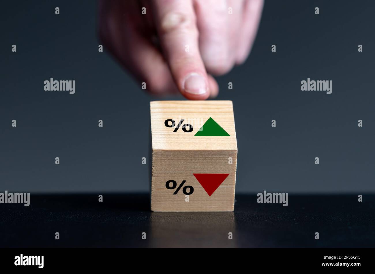 Simbolo dell'andamento del tasso di interesse. La mano gira il cubo di legno e cambia l'orientamento di una freccia da basso verso l'alto. Foto Stock