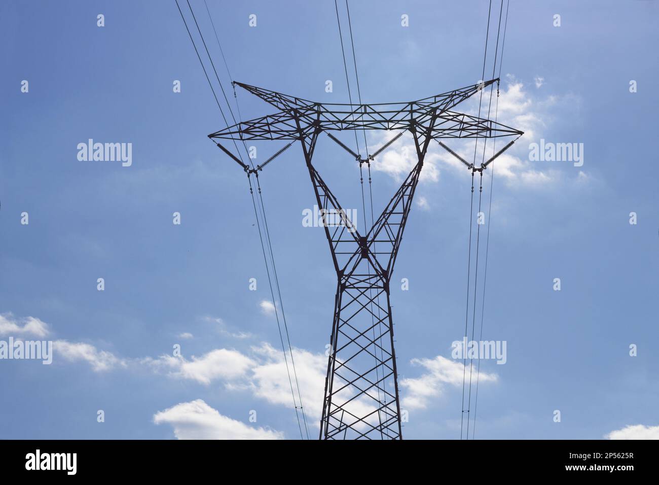 Immagine di una torre di trasmissione elettrica ad alta tensione vista da terra con cielo blu con nuvole sparse sullo sfondo Foto Stock