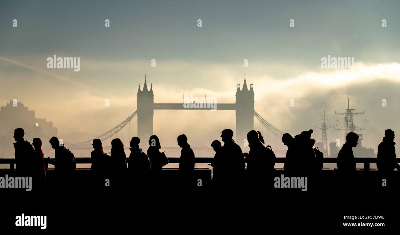 I pendolari della città attraversano il London Bridge con il Tower Bridge sullo sfondo durante una drammatica e misteriosa mattinata di febbraio. Foto Stock