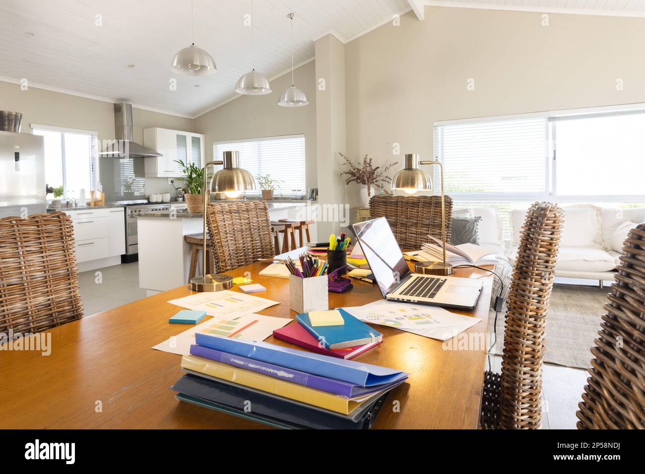 Vista generale del soggiorno e della cucina con computer portatile e documenti sul tavolo Foto Stock