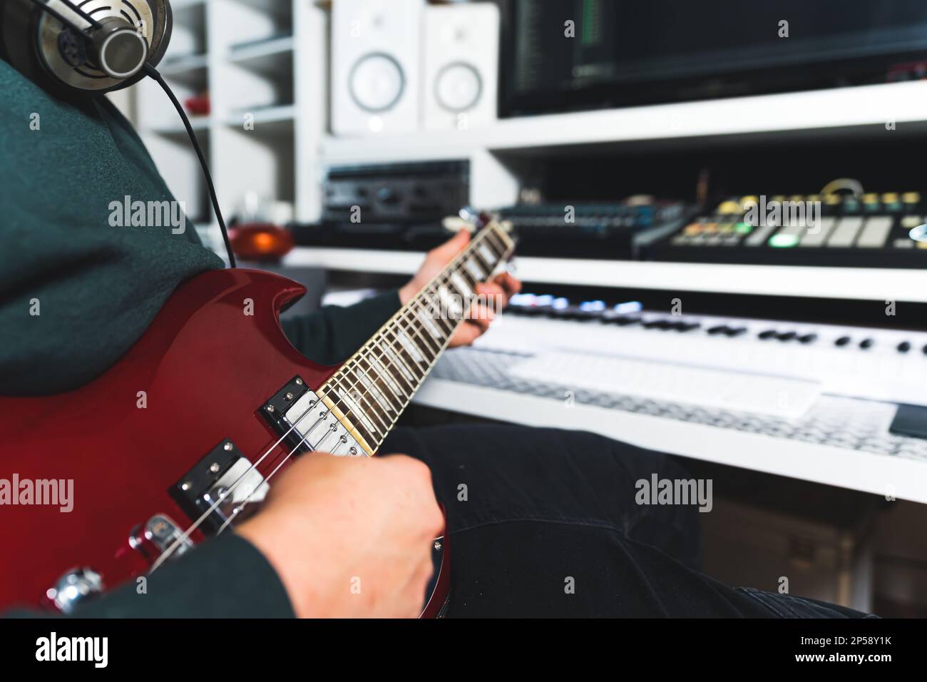 musicista sconosciuto con cuffie che suonano la chitarra basso in uno studio di registrazione a casa. Foto di alta qualità Foto Stock