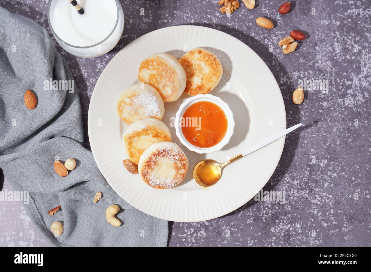 Piatto con gustosi pancake al formaggio casolare, marmellata, latte e noci su fondo grunge Foto Stock