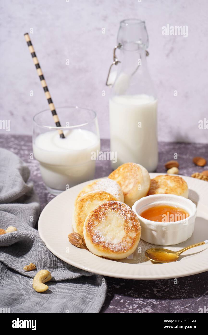 Piatto con gustosi pancake al formaggio casolare, marmellata e latte su fondo grunge, primo piano Foto Stock