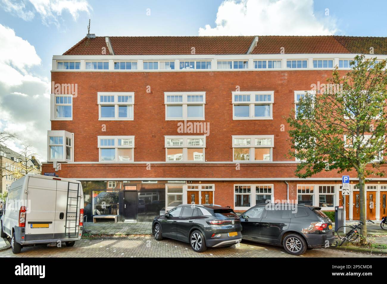 Amsterdam, Paesi Bassi - 10 aprile, 2021: Un edificio di appartamenti con auto parcheggiate sulla strada di fronte ad esso e un furgone è parcheggiato accanto ad esso Foto Stock Amsterdam, Paesi Bassi - 10 aprile, 2021: Un edificio di appartamenti con auto parcheggiate sulla strada di fronte ad esso e un furgone è parcheggiato accanto ad esso Foto Stock