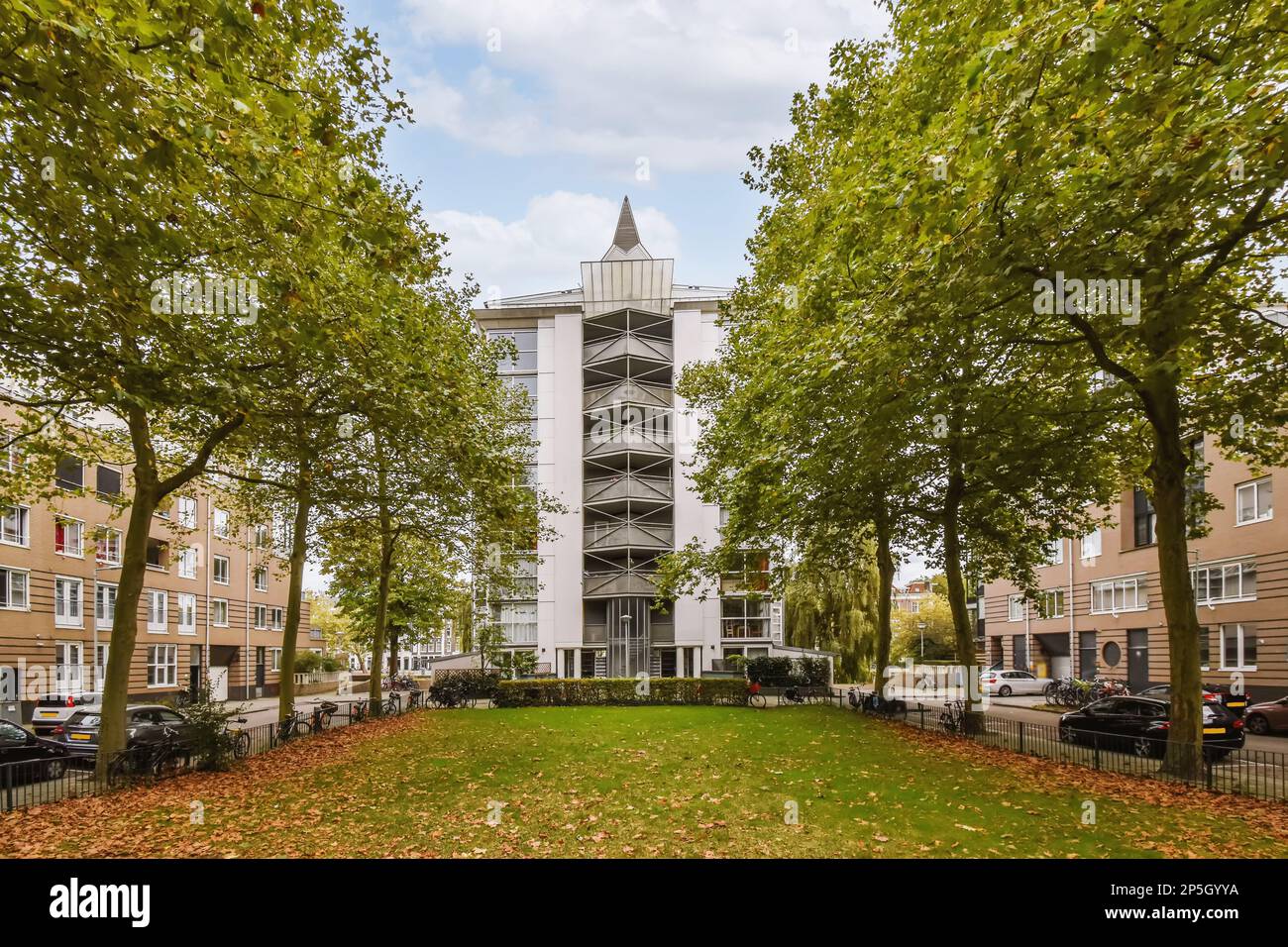 Amsterdam, Paesi Bassi - 10 aprile, 2021: Complesso di appartamenti con alberi e foglie sul terreno di fronte, vi è un grande edificio bianco Foto Stock