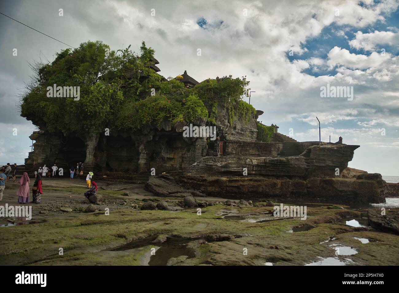 Foto di tutto il tempio pura Tanah Lot, rocce in primo piano, il mare sullo sfondo. Foto Stock