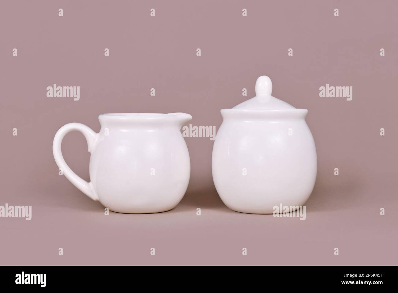 Caraffa bianca per creamer e recipiente per lo zucchero su sfondo beige Foto Stock