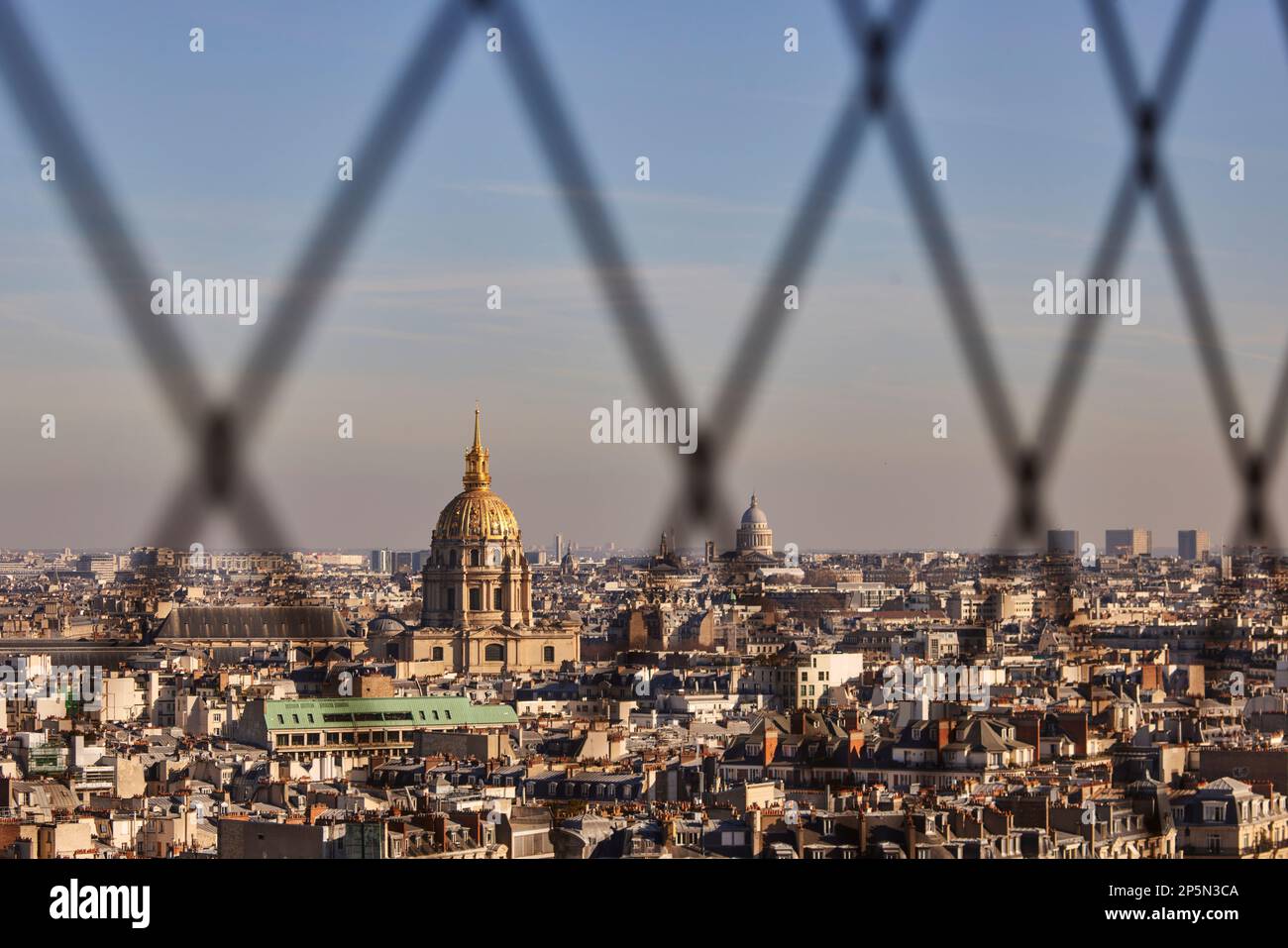 Simbolo di Parigi, i tetti che incorniciano la cupola dorata di Les Invalides e la tomba di Napoleone attraverso la rete della Torre Eiffel Foto Stock