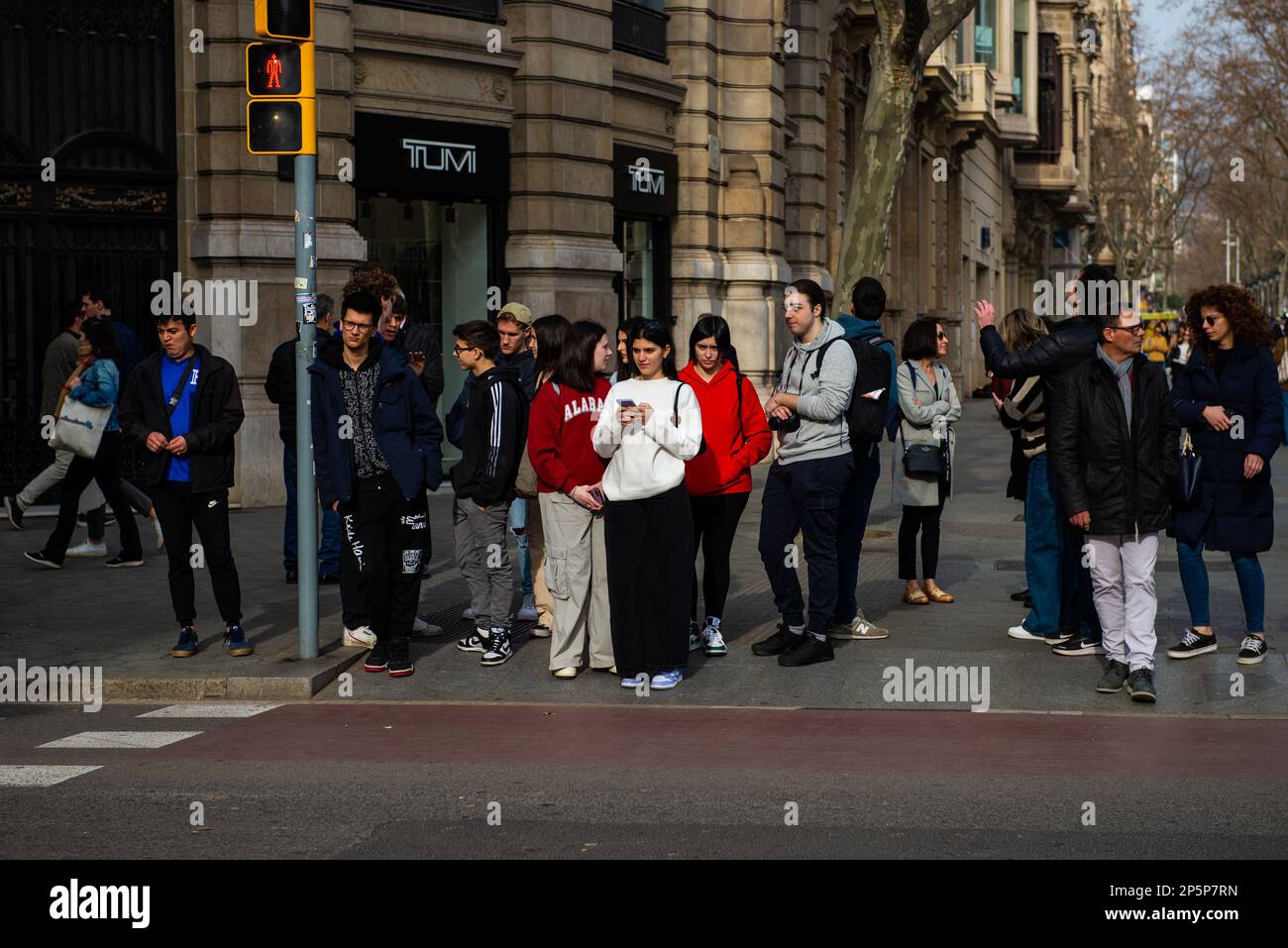 Barcellona, Spagna-Febbraio 22,2023:i pedoni aspettano ad un incrocio di strada trafficato mentre parlano tra loro. Foto Stock