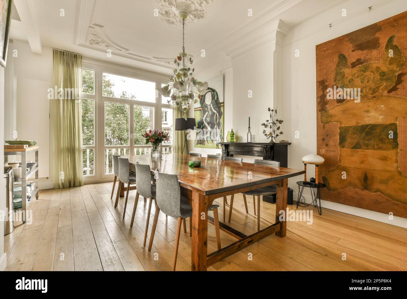 una sala da pranzo con pavimento in legno e un pezzo d'arte appeso alla parete nella stanza è decorata con fiori Foto Stock